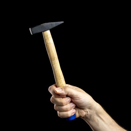Hand holding a hammer on a dark background.