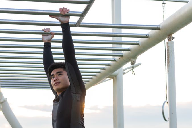 Asian sportsman exercising on monkey bars