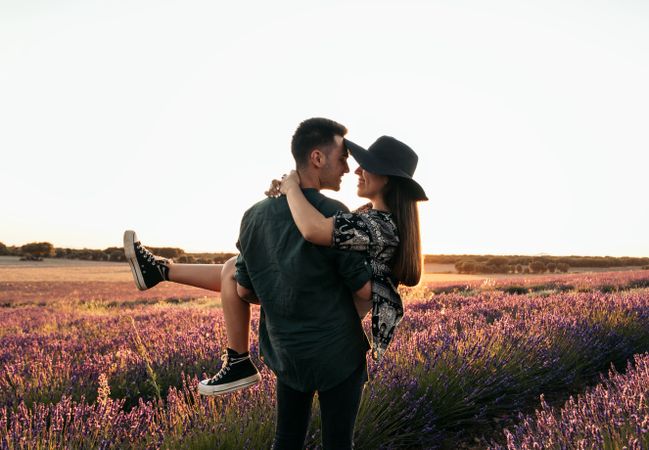 Beautiful romantic photo of a couple in a field of flowers at sunset