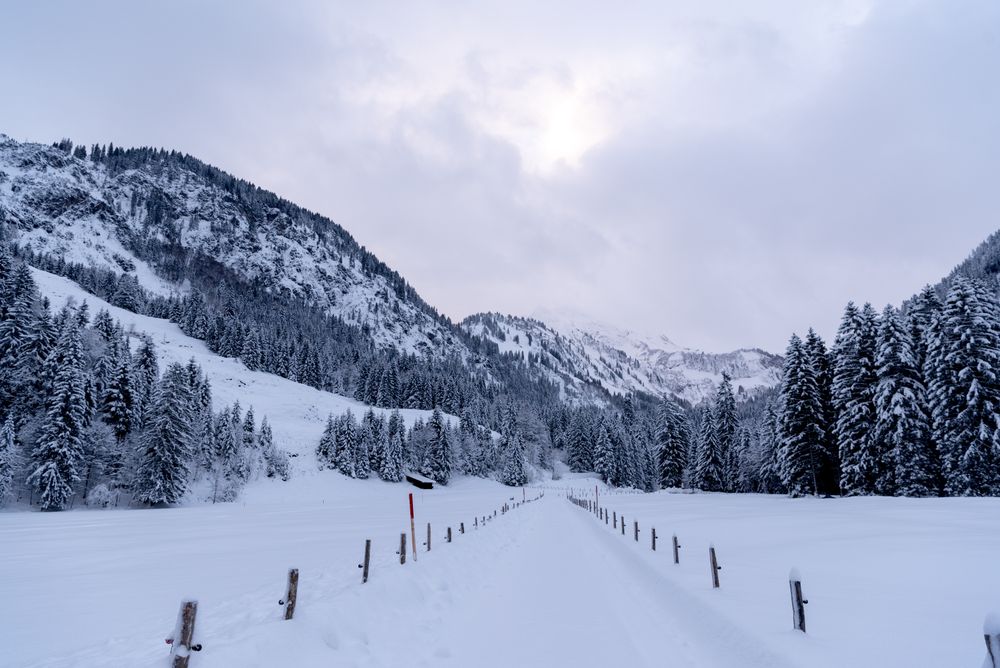Snow-covered road passing through an alpine valley in the Bavarian Alps, Germany