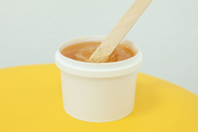 Liquid yellow paste for sugaring on yellow background, space for text