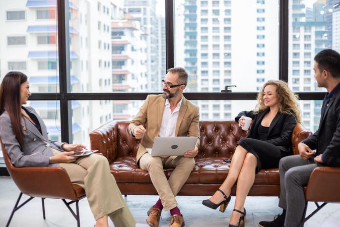 Businesspeople meeting in modern workplace on leather couch