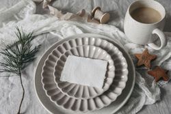 Card, invitation mockup on ceramic plate with pine cone and cookies on tablecloth