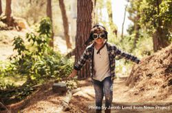 Child with pilot goggles and hat running outdoors in forest 4MNYzb