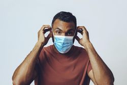 Male adjusting medical face mask in studio shoot