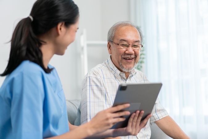 Patient smiling as medical professional shows him something on tablet