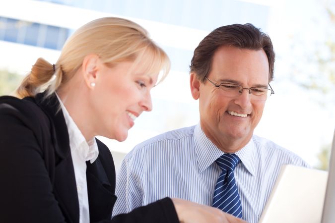 Businessman and Female Colleague Using Loptop Outdoors