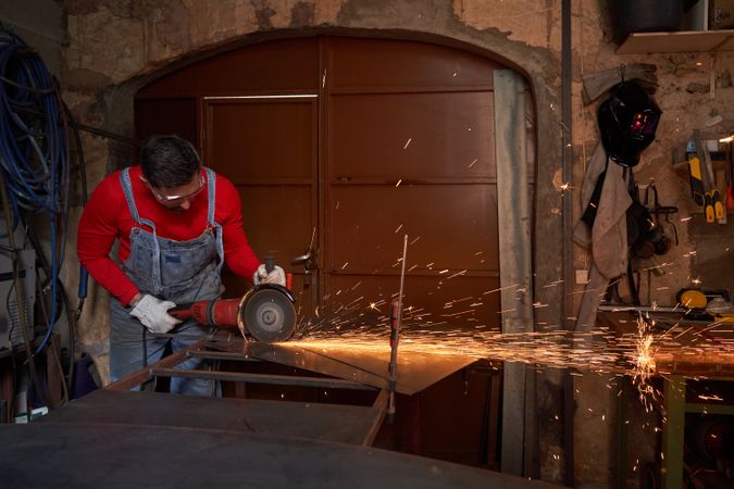 Master cutting metal on workbench with angle grinder