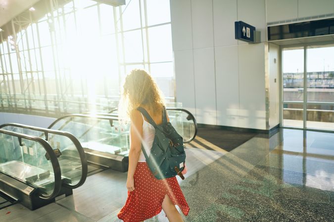 Active woman standing at escalator and about to go down