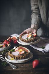 Chef serving plate of strawberry and citrus cake on table