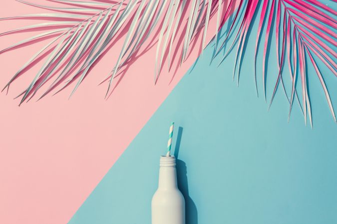 Tropical painted leaves and drink on pink and blue background