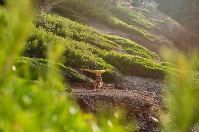 Unrecognizable female athlete doing yoga on cliff