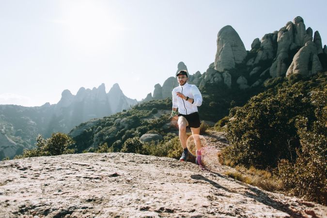 Male running on rugged terrain outside for ultra trail marathon