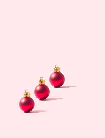 Three red round ornaments on a pink background