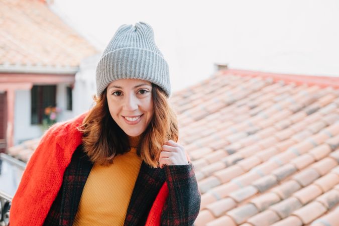 Positive woman in warm wear near house