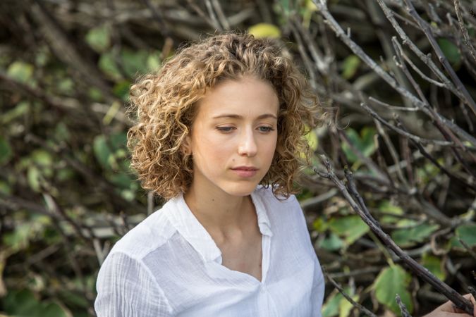 Young woman near dry twigs of bushes