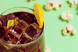Popcorn on table near drink in glass with ice and lemon