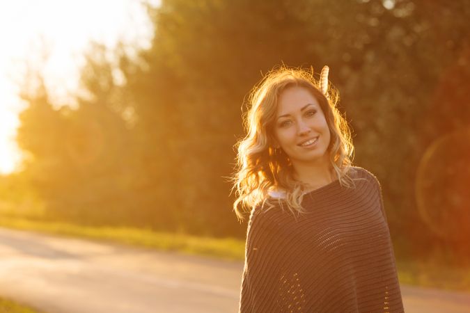 Smiling female standing on country road at dusk