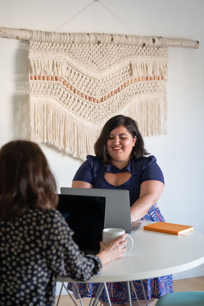 Two women facing each other working on laptops
