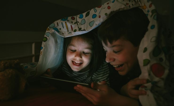 Siblings looking at the tablet in the dark