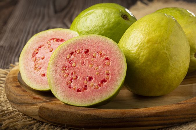 Fresh sliced guavas on wooden table.