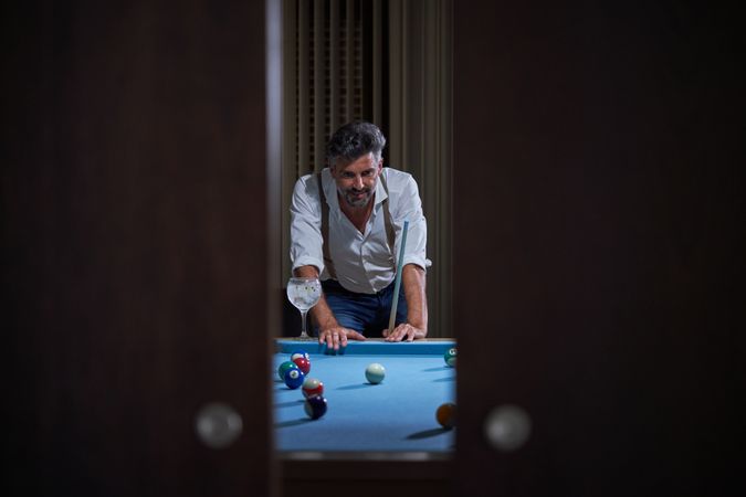 Male with cue playing billiards at home