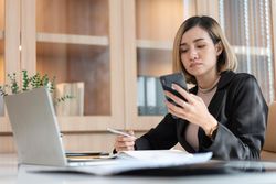 Asian female manager checking phone at work