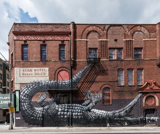 Whimsical alligator wall mural on red brick building