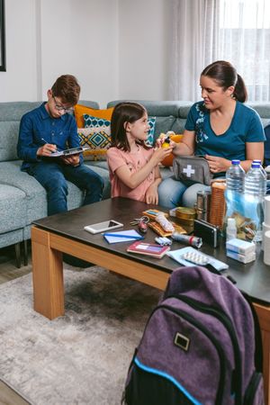 Mother preparing emergency backpack with her children