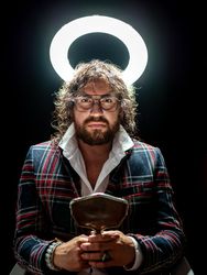 Serious man with glowing fake nimbus holding mirror and looking at camera