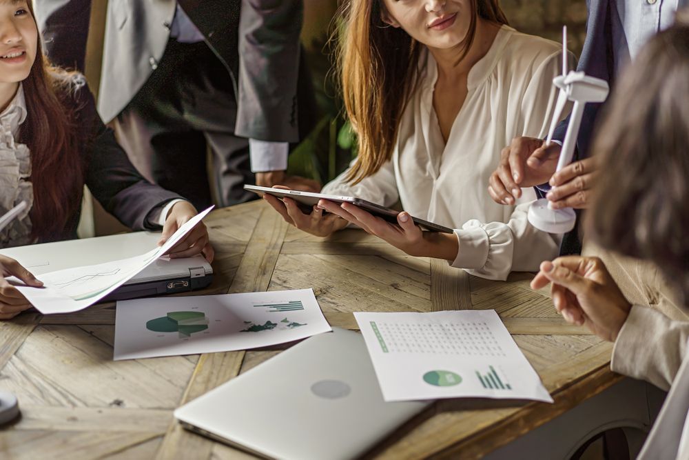 Group of co-workers talking about a project with charts & documents