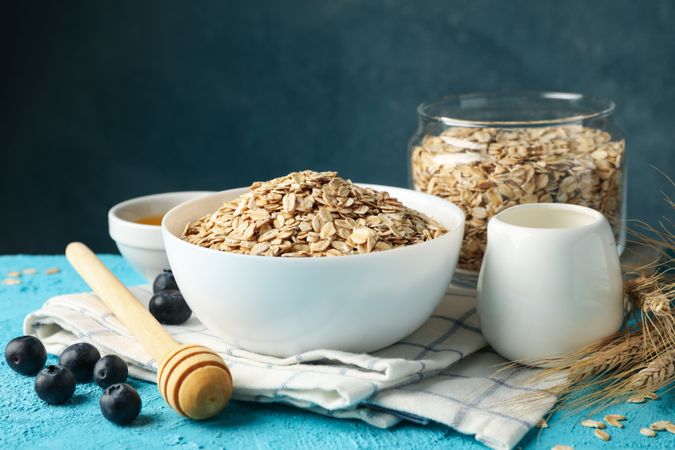 Composition with oatmeal flakes on blue background. Cooking breakfast