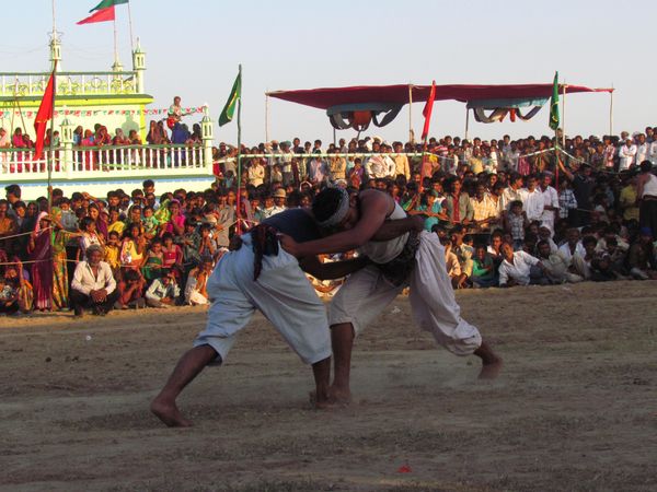 Two Indian men fighting in an outdoor arena while audience watching