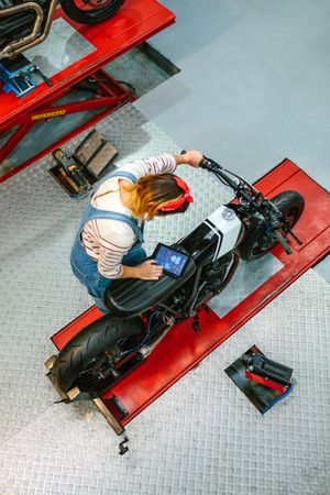 Mechanic woman using diagnosis app to review custom motorcycle