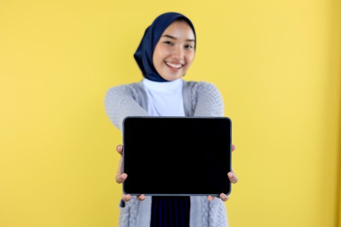 Cheerful Young Asian Indonesian Woman in Hijab Demonstrating Tablet Screen Mockup