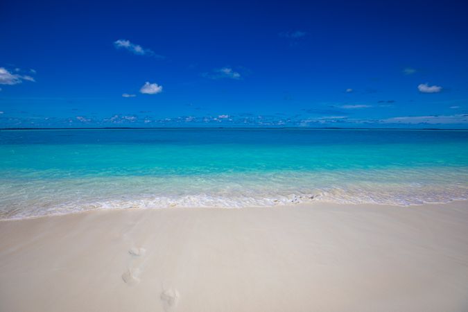 A clear blue beach with footprints