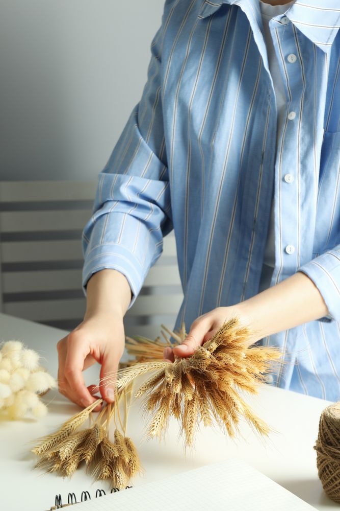 Woman in blue striped shirt arranging dried flowers, vertical