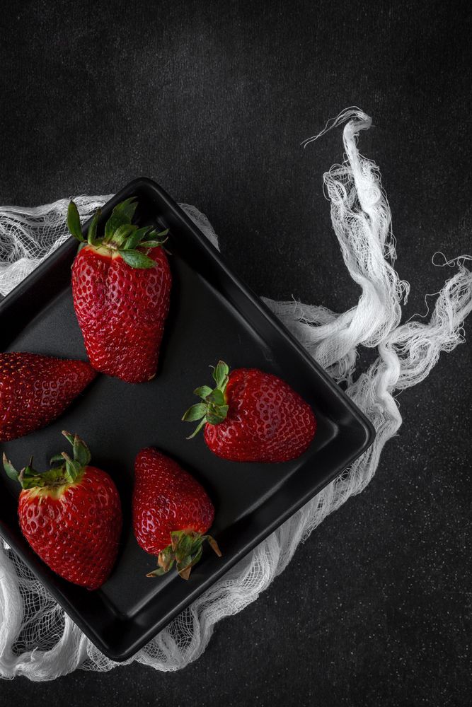 Red and fresh strawberries flat lay in dark dish