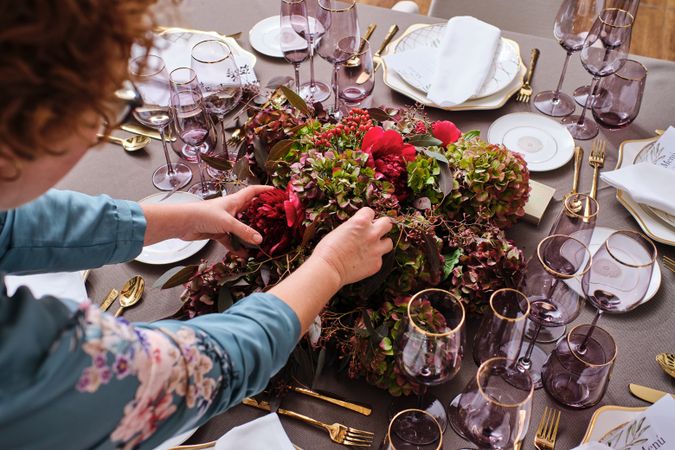Unrecognizable woman arranging flowers on festive table