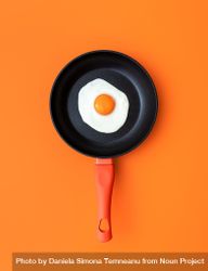 Fried egg in a cooking pan, top view on an orange background 4OVnE5