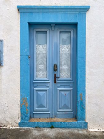 Patmian blue door with lace curtains