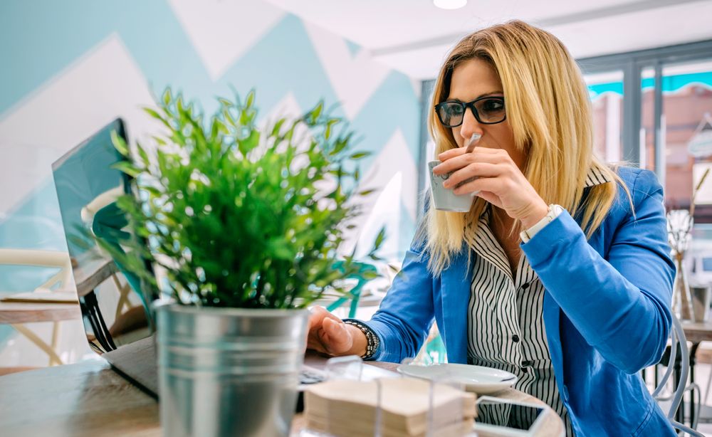 Woman drinking coffee and working with the laptop