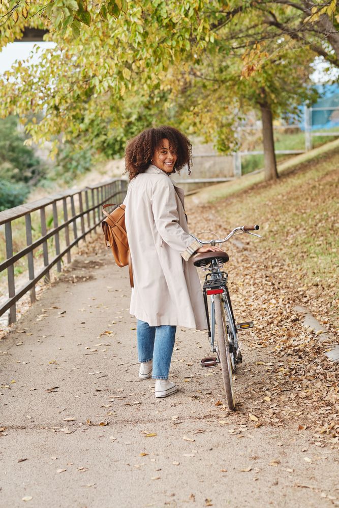 Smiling female with bicycle in autumn park