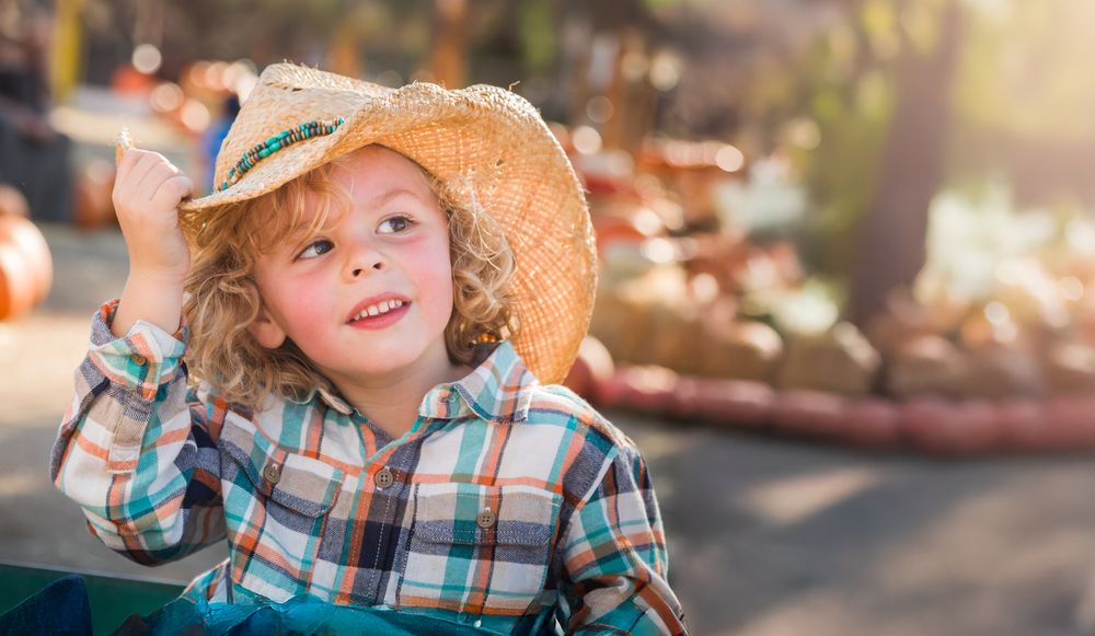 Cute Young Boy Wearing Cowboy Hat at Pumpkin Patch Farm.