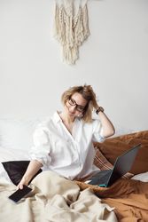 Woman Working From Home In Bed With Phone