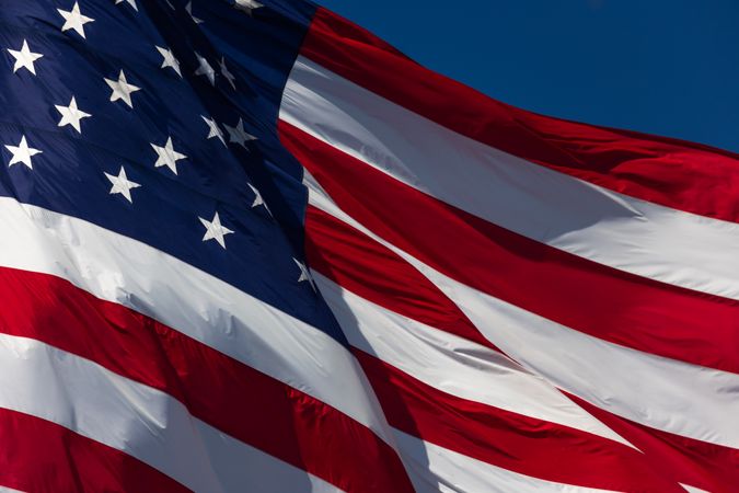 American Flag Waving In The Wind Against Deep Blue Sky.