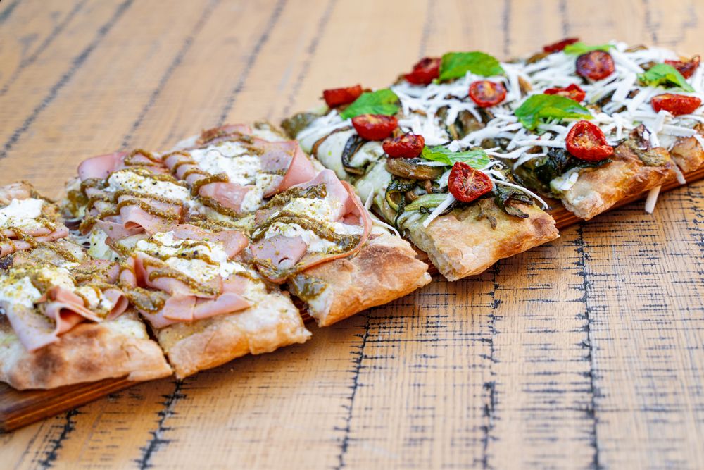 Gourmet Italian Pizza Slices with Ham, Vegetables, and Cheese on Rustic Wooden Board
