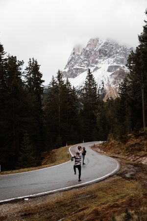 Casual resting couple standing in an embrace on route amid forest