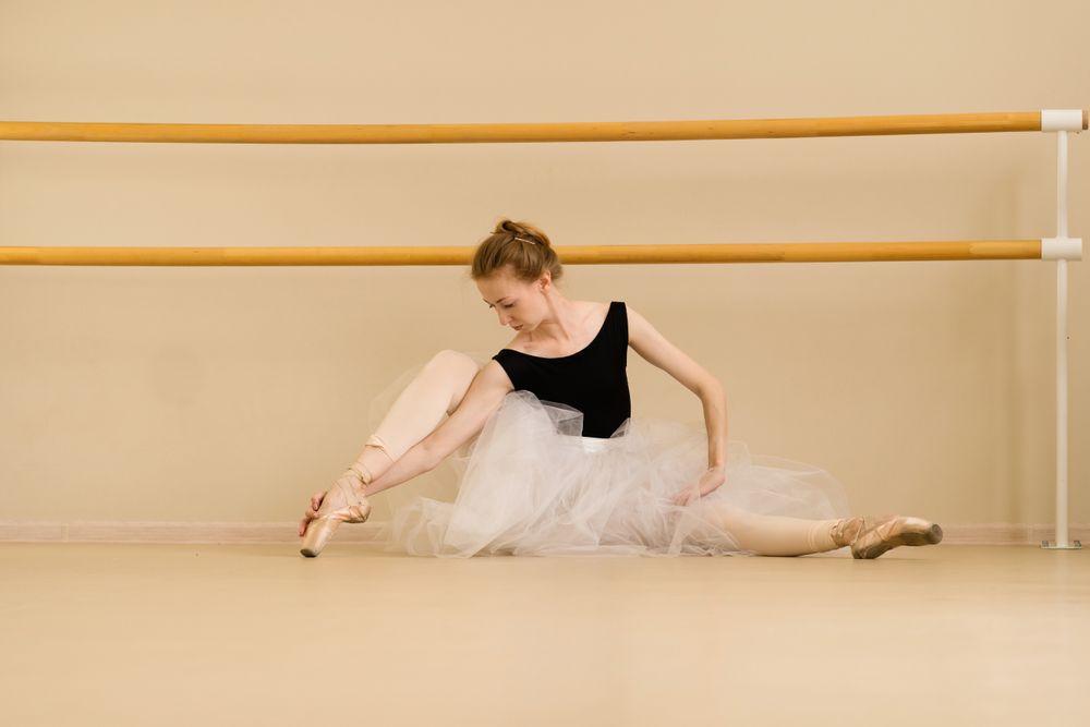 Ballet dancer elegantly poses on floor, showcasing artistry and poise