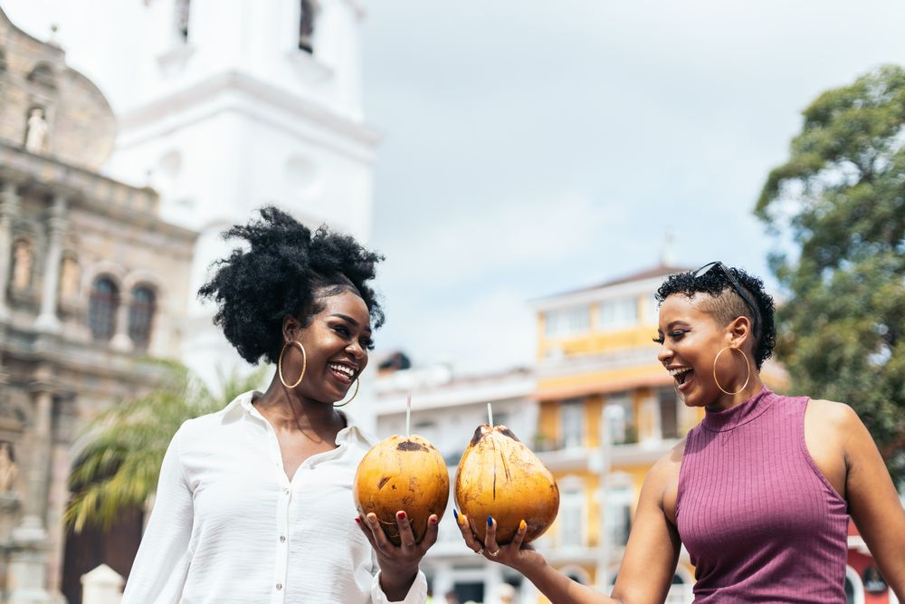 Latin American women having fun in the city drinking coconuts